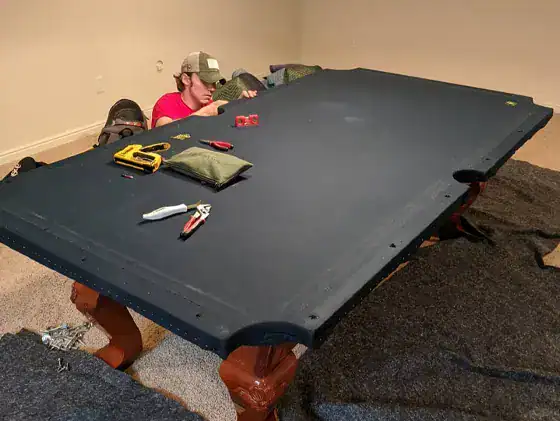 a member of Manly Moving disassembling a pool table